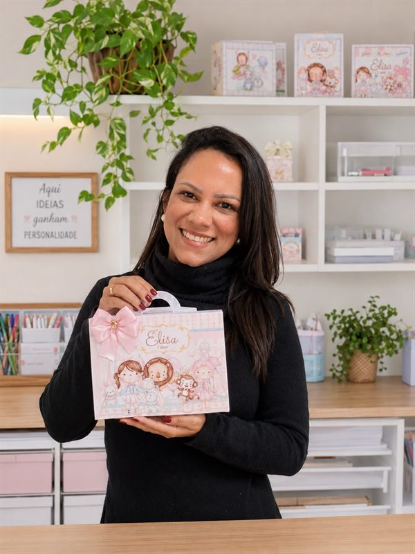 Naty Costa no ateliê segurando uma maleta personalizada
